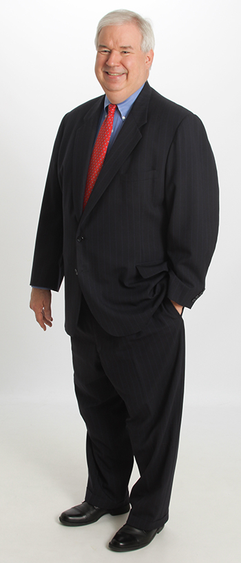 Legend’s Lou Stanasolovich professional biography picture, standing head to toe in a professional suit in front of a white background.