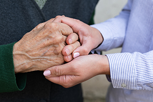 Close up picture of caregiver holding senior woman's wrinkled hands