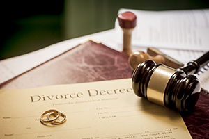 A divorce decree along with two rings and a gavel.